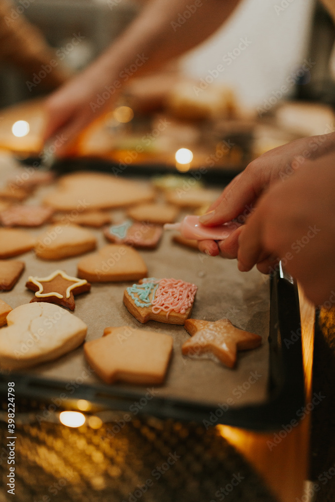 Christmas baking. Cooking Christmas gingerbread. Damily decorating freshly baked cookies with icing, close up. Festive food, family culinary, Christmas and New Year traditions concept