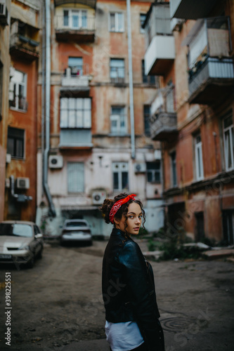 Young woman walks and looks back on narrow city street.