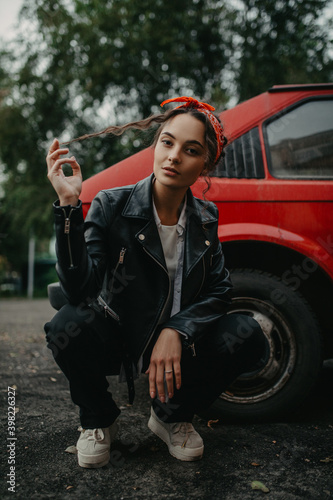 Young woman sits on street near retro car.