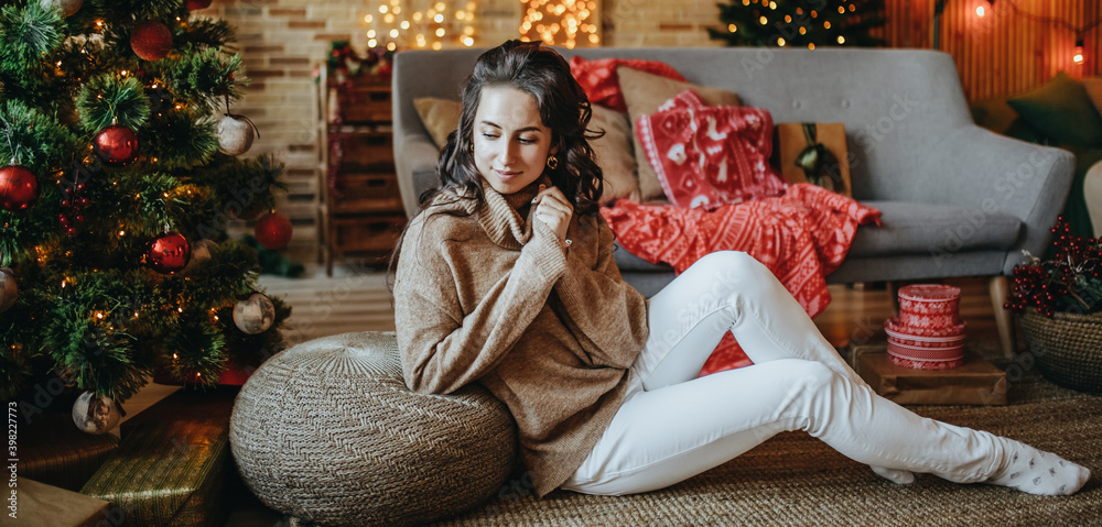 © Daria Lukoiko - Beautiful cheerful happy young girl with christmas gifts on sofa on the background of a new year tree at home