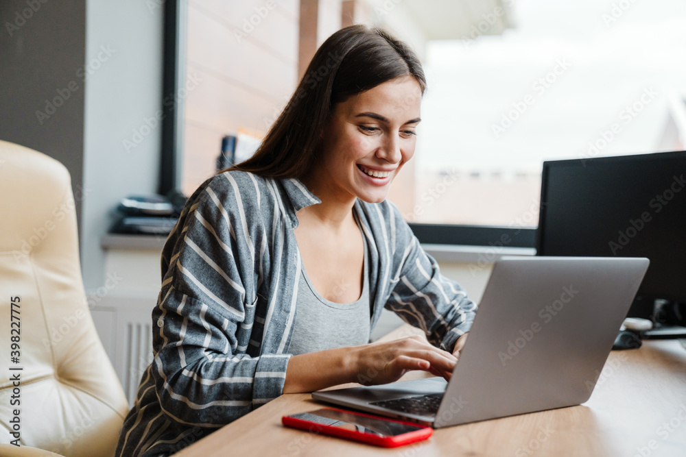 Charming happy woman smiling while working with laptop at home Charming happy woman smiling while working with laptop at home