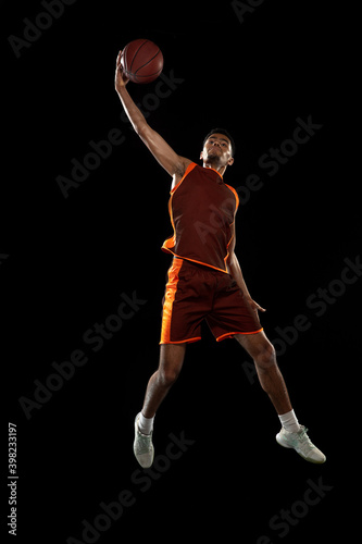 High. Young purposeful african-amrican basketball player training, practicing in action, motion isolated on black background. Concept of sport, movement, energy and dynamic, healthy lifestyle. © master1305