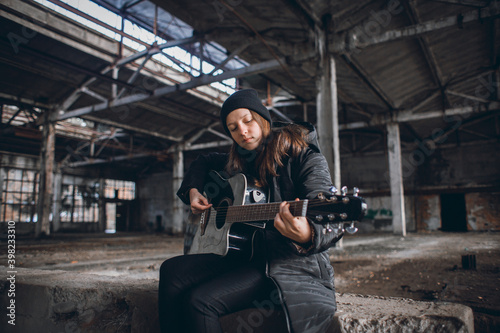 Young Girl Playing Guitar in an Abandoned Hall