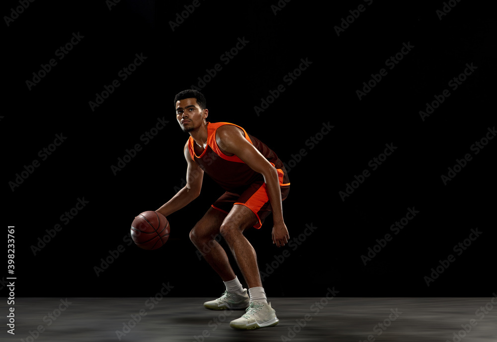 Winner. Young purposeful african-amrican basketball player training, practicing in action, motion isolated on black background. Concept of sport, movement, energy and dynamic, healthy lifestyle.