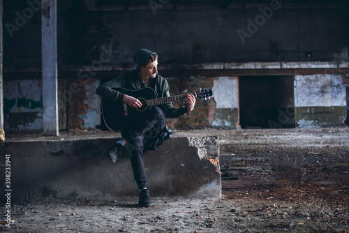 Young Boy with Guitar in Empty Grunge Hall