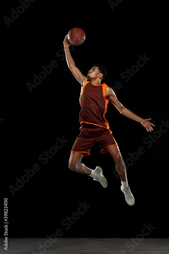 Overcome. Young purposeful african-amrican basketball player training, practicing in action, motion isolated on black background. Concept of sport, movement, energy and dynamic, healthy lifestyle. © master1305