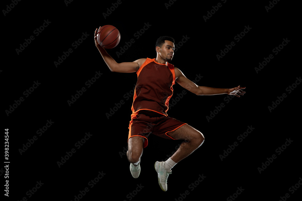 Speed. Young purposeful african-amrican basketball player training, practicing in action, motion isolated on black background. Concept of sport, movement, energy and dynamic, healthy lifestyle.
