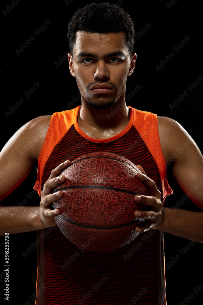 Preparing. Young purposeful african-amrican basketball player training, practicing in action, motion isolated on black background. Concept of sport, movement, energy and dynamic, healthy lifestyle.