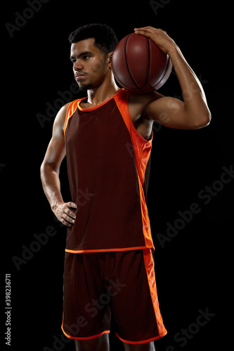 Strong. Young purposeful african-amrican basketball player training, practicing in action, motion isolated on black background. Concept of sport, movement, energy and dynamic, healthy lifestyle.