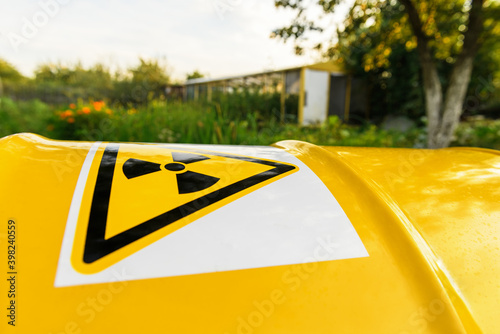 .Radiation hazard symbol sign, close up. The nuclear sign on a yellow metal rusty barrel on the green grass. Dirty barrel of chemical waste