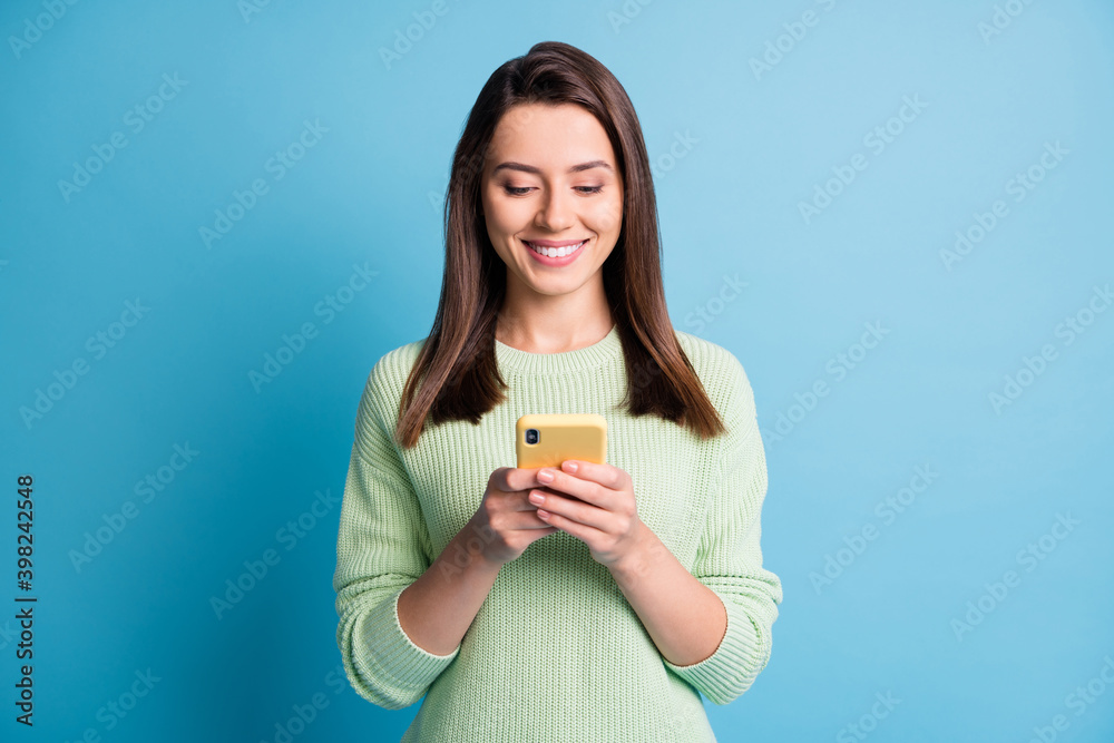 Photo portrait of girl texting holding yellow phone in two hands isolated on pastel blue colored background Photo portrait of girl texting holding yellow phone in two hands isolated on pastel blue colored background