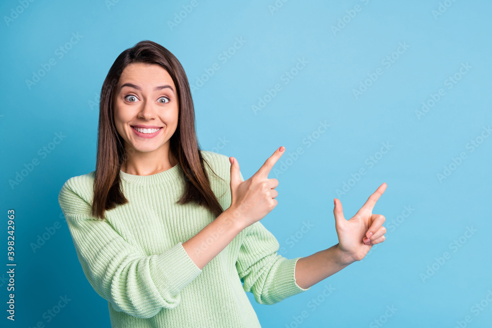 Photo of pretty young girl direct fingers empty space funny face wear green pullover isolated blue color background Photo of pretty young girl direct fingers empty space funny face wear green pullover isolated blue color background