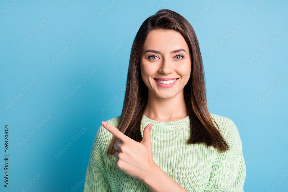 Photo of charming young lady indicate finger empty space toothy smile wear green sweater isolated blue color background