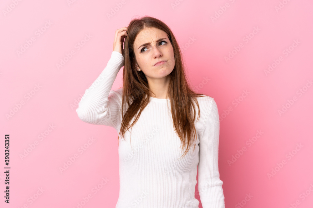 Young woman over isolated pink background having doubts while scratching head Young woman over isolated pink background having doubts while scratching head
