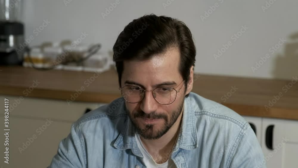 Close-Up of a Young European Man Talking to a Colleague, Working Online at Home in the Kitchen Close-Up of a Young European Man Talking to a Colleague, Working Online at Home in the Kitchen