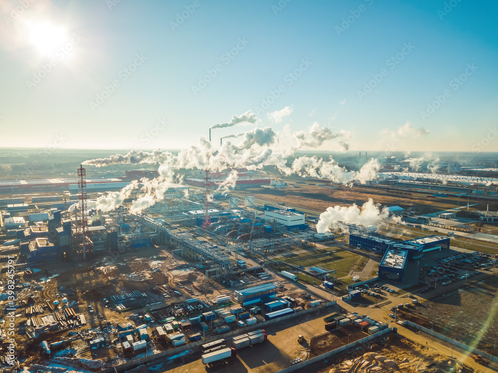 Factories, pipes with smoke on a Sunny snowless winter day close up, photo from a drone. Concept of ecology and nature protection