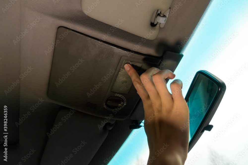 Woman's hand turns on the interior lighting in the car close-up