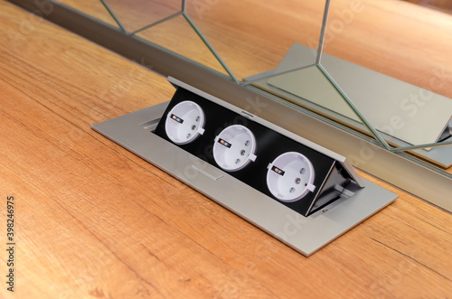 Three hidden sockets on a wooden kitchen countertop close-up, copy space photo