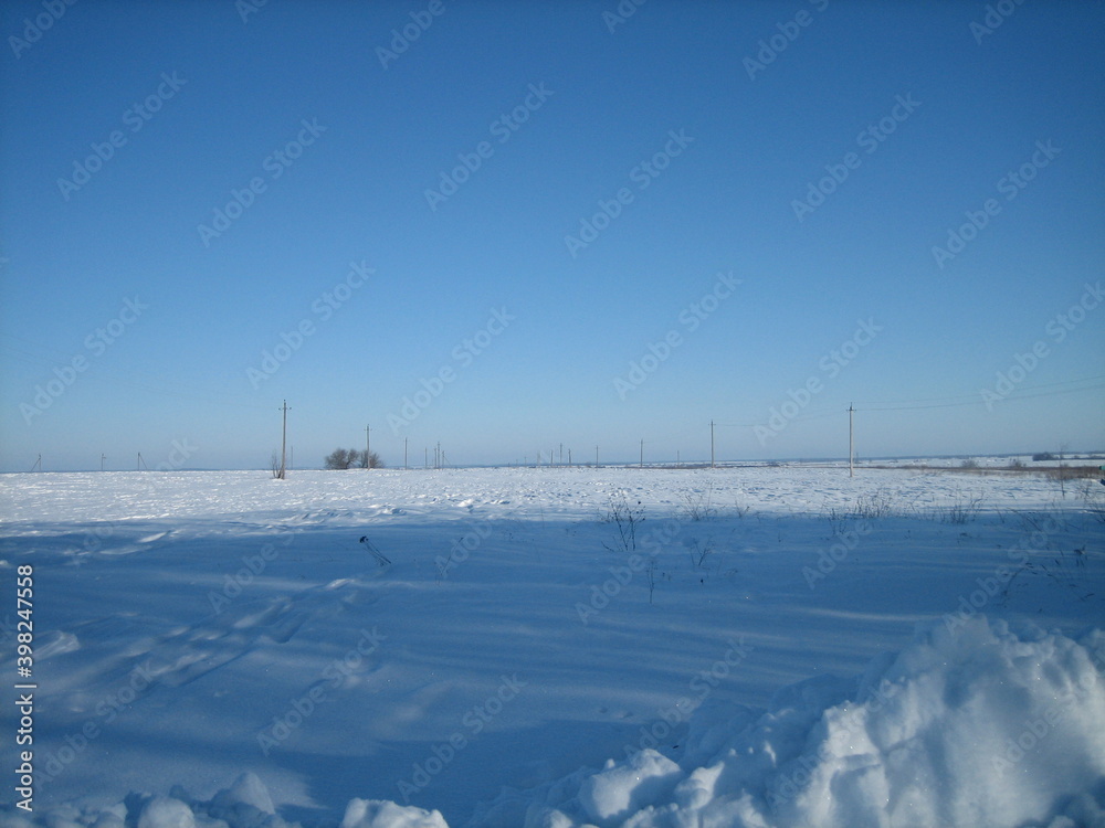 Clear snow field on a clear frosty day. Only in the distance, on a flat horizon, is the forest visible.
