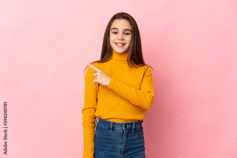 Little girl isolated on pink background pointing to the side to present a product Little girl isolated on pink background pointing to the side to present a product