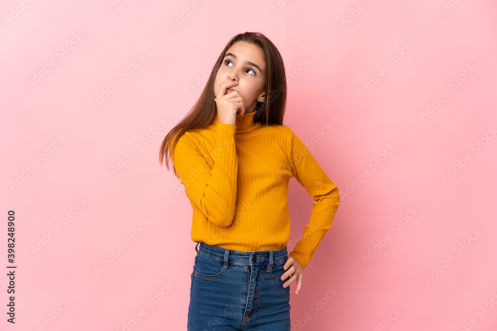 Little girl isolated on pink background having doubts and with confuse face expression Little girl isolated on pink background having doubts and with confuse face expression