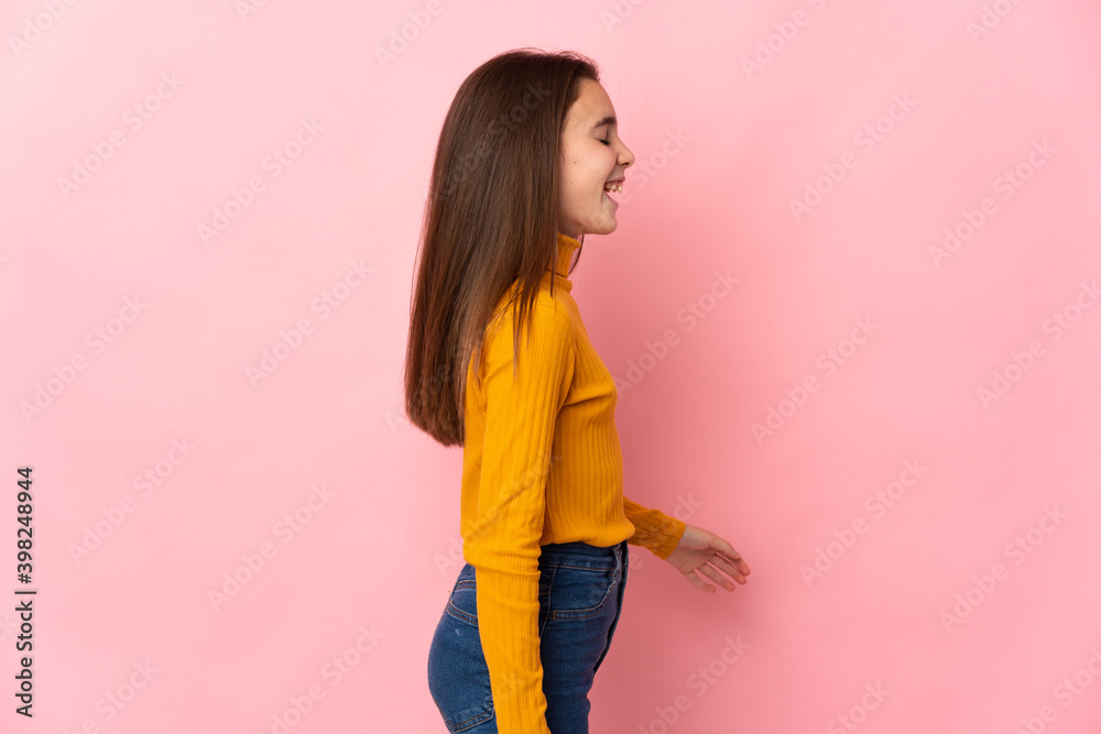 Little girl isolated on pink background laughing in lateral position Little girl isolated on pink background laughing in lateral position