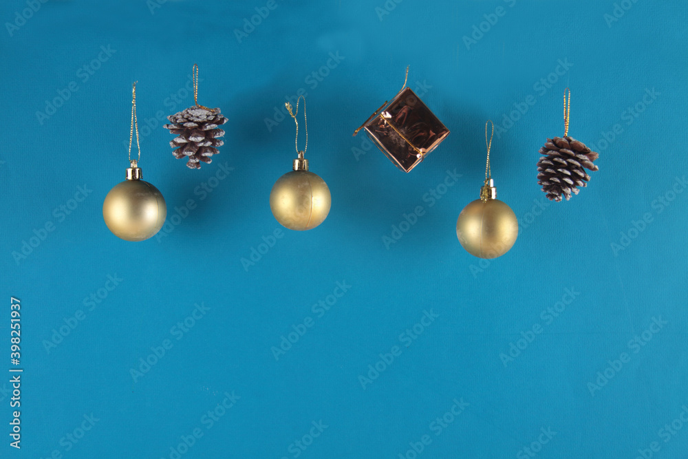 golden christmas balls, fir-cones and a gift isolated on blue background. Christmas decoration concept golden christmas balls, fir-cones and a gift isolated on blue background. Christmas decoration concept