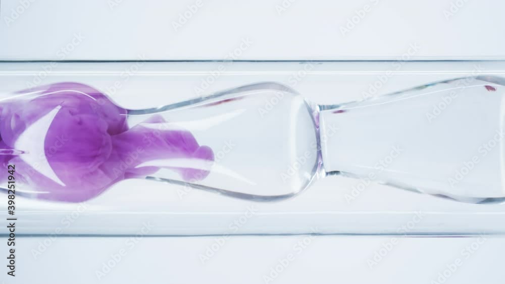 Pink liquid substance flows through a glass flask. Concept for advertising perfume and cosmetic products. Mixing pink ink with water in a large laboratory glass test tube.