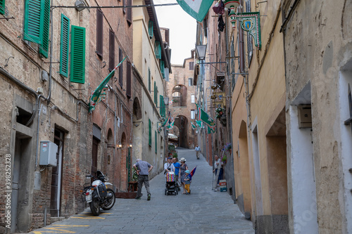 Walking on narrow street in Siena city with historic buildings and shops