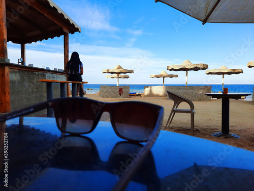 Sunglasses lie on the table near the beach bar