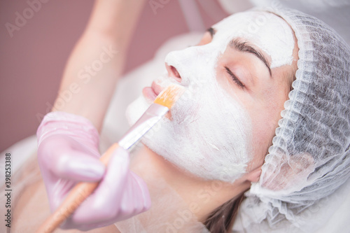 The girl is given a mask on her face in the salon. Cosmetology, skin care, salon. 