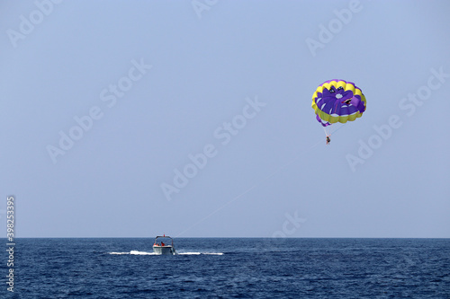 Parasailing on the sea, people flying on parachute. Concept of vacation, extreme sports on a beach