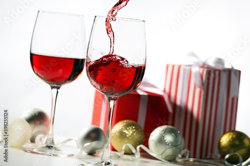 Beautiful splash of red wine in glasses on the background of Christmas gifts and Christmas balls
