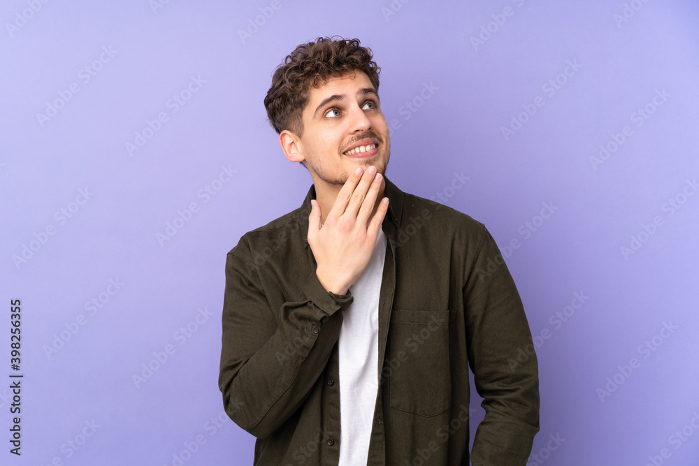 Caucasian man isolated on purple background looking up while smiling Caucasian man isolated on purple background looking up while smiling