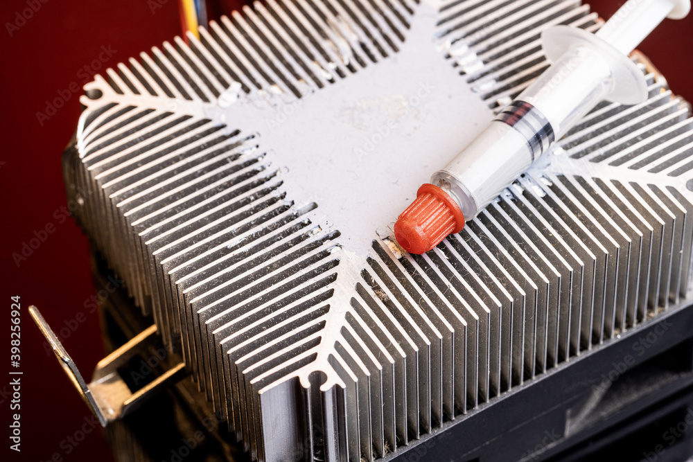 Fototapeta premium thermal paste at syringe package over dark red gradient background. copy space. studio shot. thermally paste for computer hardware