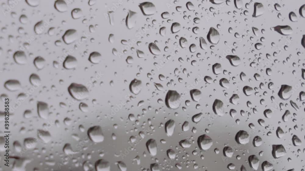 Extreme closeup of large raindrops on window with grey background Extreme closeup of large raindrops on window with grey background