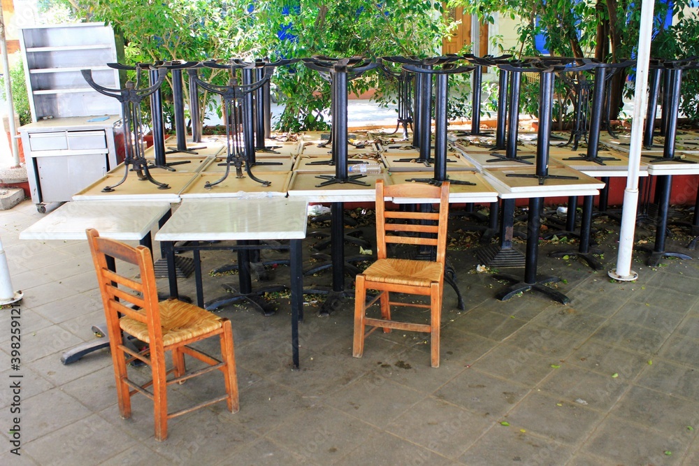 Tables and chairs stacked outside closed cafe-restaurant due the Coronavirus lockdown - Athens, Greece, May 6 2020.