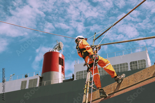 Rope access and abseiling worker on high wear dresses and safety man with harness concept on steel structures success from work in site construction on blue sky background.