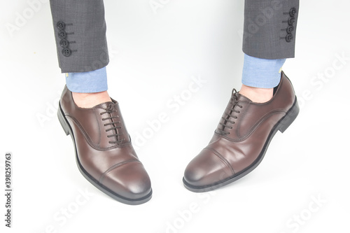 Classic brown leather shoes worn on the hands on a white background