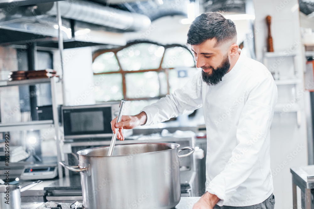 Boils water. Chef in white uniform cooking food at kitchen. Busy day at work