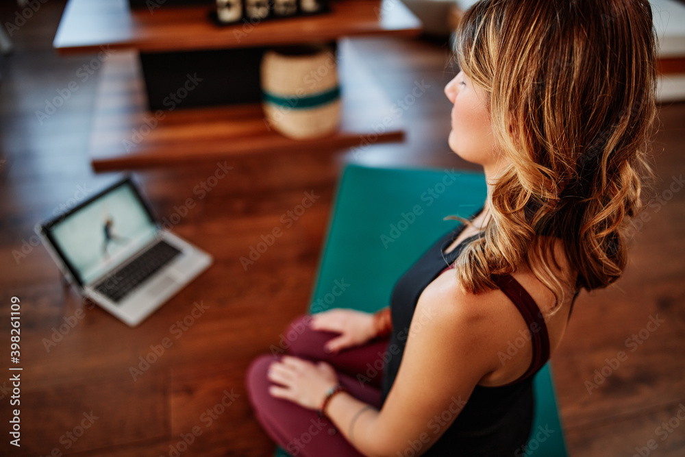 A middle-aged yogi woman practicing yoga at home, following online tutorial during corona virus. A middle-aged yogi woman practicing yoga at home, following online tutorial during corona virus.