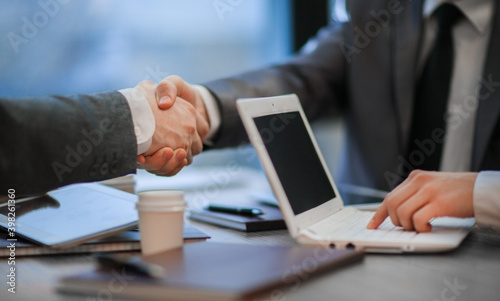 business colleagues shaking hands over a work Desk. close up.