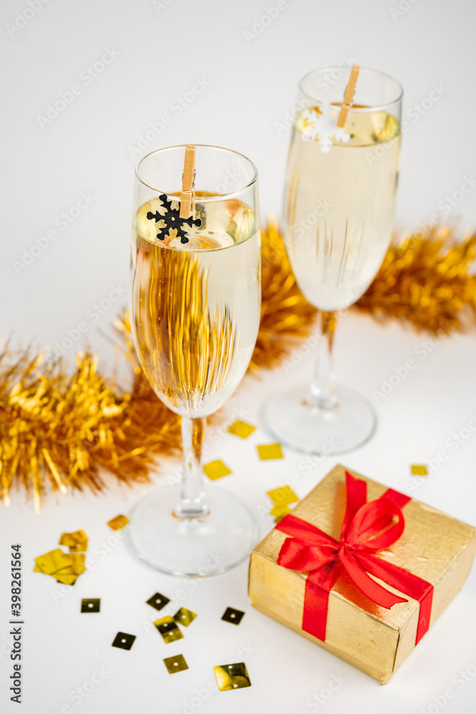 Two glasses with champagne, gold gift box and Christmas decoration with snowflakes on white background Two glasses with champagne, gold gift box and Christmas decoration with snowflakes on white background