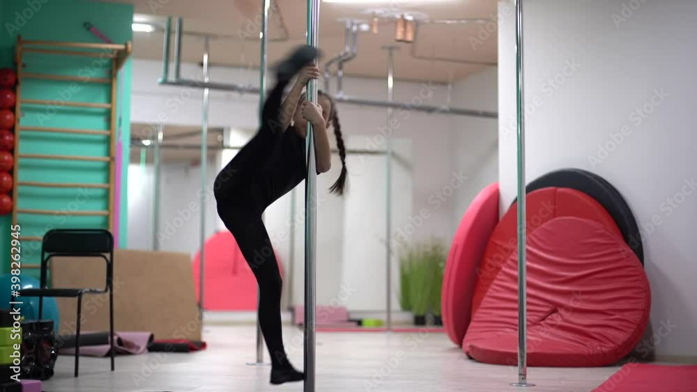 little girl has fun on pylon at pole dance studio