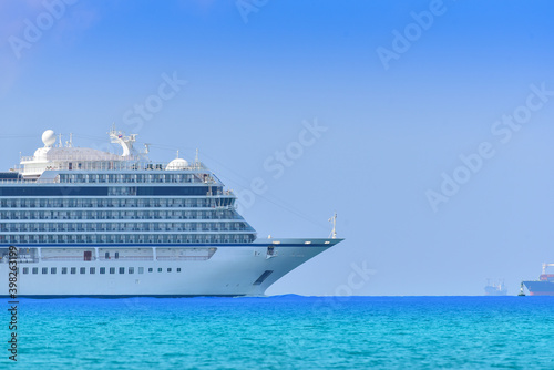 Cruise ship and sideship forward, large luxury white cruise ship liner on blue sea water go from port of shipping terminal to ocean and sunset background.