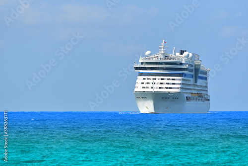 Front view of Cruise ship, large luxury white cruise ship liner on blue sea water and cloudy sky background. © TawanSaklay