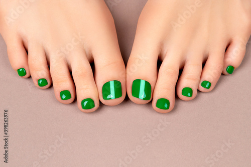 Beautiful womans legs with sping summer nail design on neutral color background