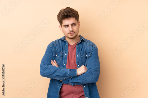 Caucasian man isolated on beige background thinking an idea