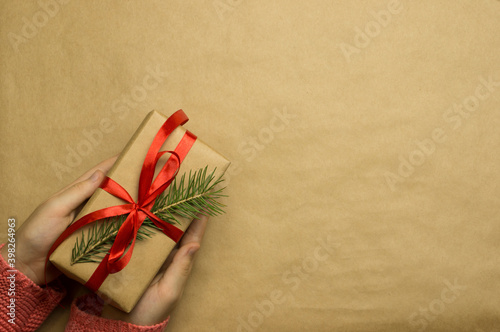 Girl's hands hold a gift wrapped in craft paper photo