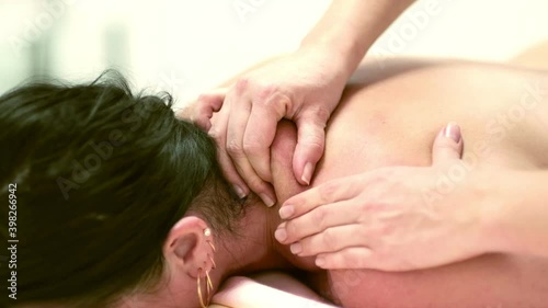 Physical Therapist Massaging the Back and Shoulder of a Female Patient. Over shoulder view of masseur performing deep tissue massage. 4k stock footage. close up video. Slow motion video. photo